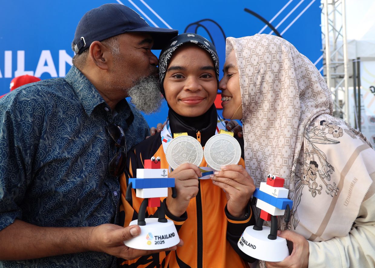Special moment: National woman archerAriana Nur Dania Mohamad Zairi (centre) together with her father Mohamad Zairi Mohamad Yusoff and mother Norashikin Mohd Kamal.— MUHAMAD SHAHRIL ROSLI/The Star
