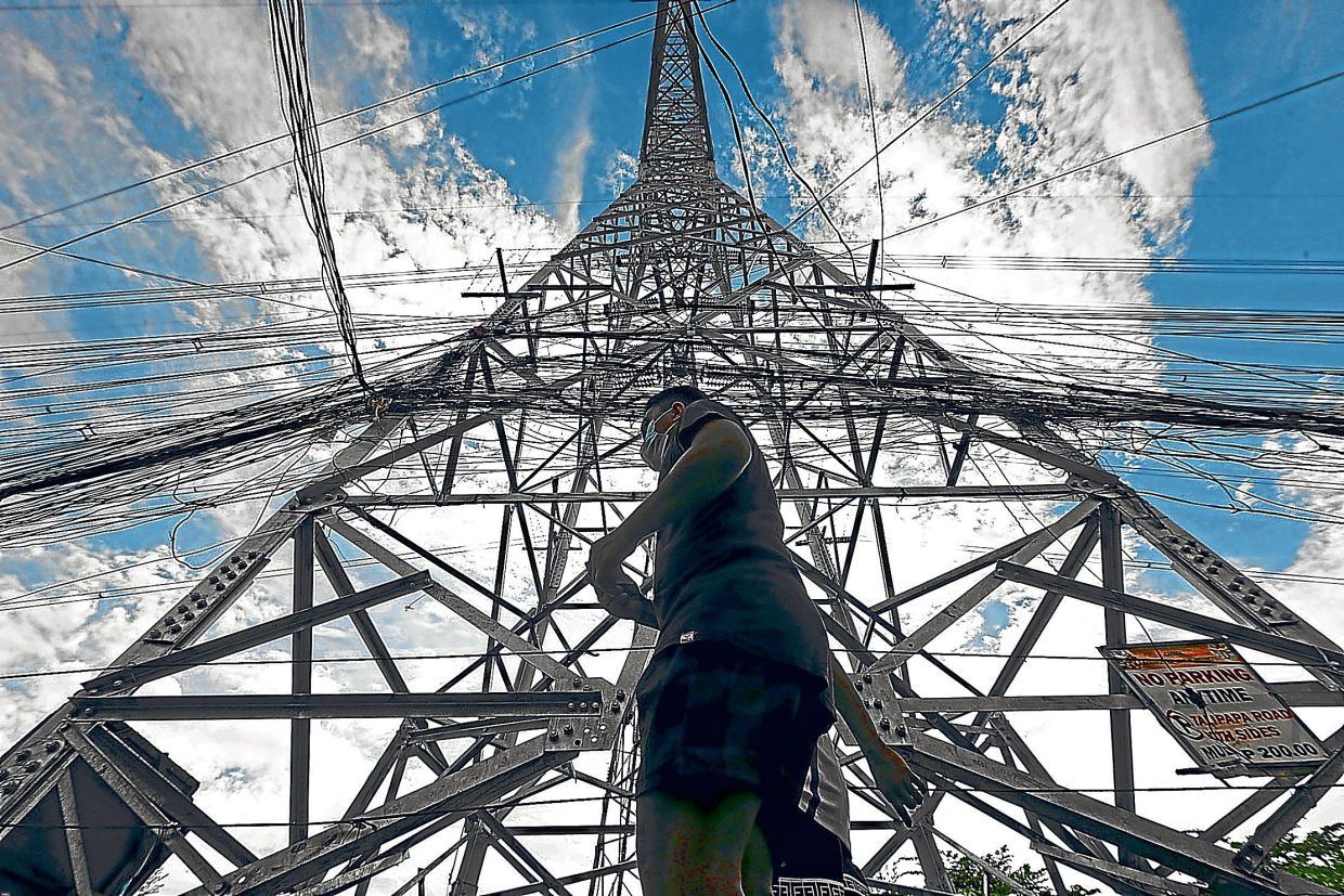 A pedestrian walks past an electric tower in this September 2022 file photo. The electrification of off-grid islands in the archipelago is not just about technology — it is about delivering justice, opportunity and resilience to communities historically left behind. — GRIG C MONTEGRANDE/Philippine Daily Inquirer