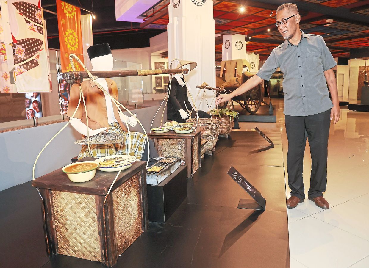 Mohd Zainudin looking at an exhibit in Muzium Shah Alam that shows how Sate Kajang used to be sold by traders who carried the ingredients from village to village on a ‘kandar’. — Photos: MUHAMAD SHAHRIL ROSLI and courtesy photos