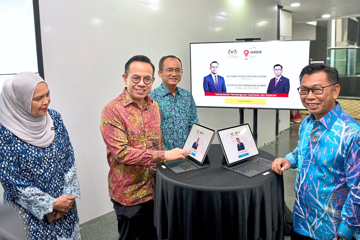 On the job: Sim (second from left) clocks in for work on his first day as the Entrepreneur Development and Cooperatives Minister. — Bernama