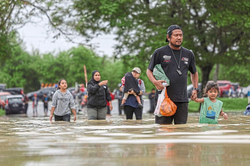 Residents wading through floodwaters around the Taman Guru area following continuous rainfall.