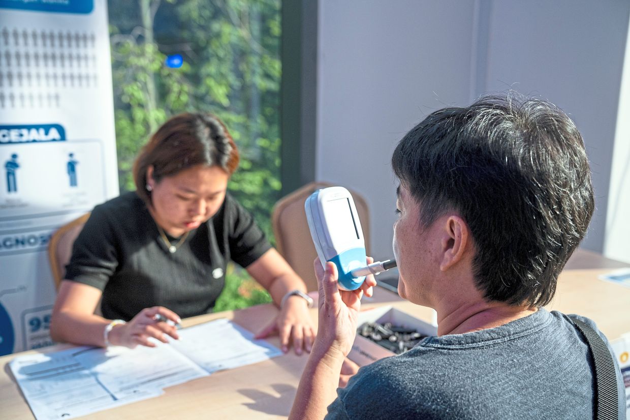 A visitor breathes into a handheld monitor that measures carbon monoxide (CO) levels in the breath – an indicator of recent tobacco smoke exposure – during NCSM’s recent corporate pop-up at The Bousteador in Petaling Jaya, Selangor.