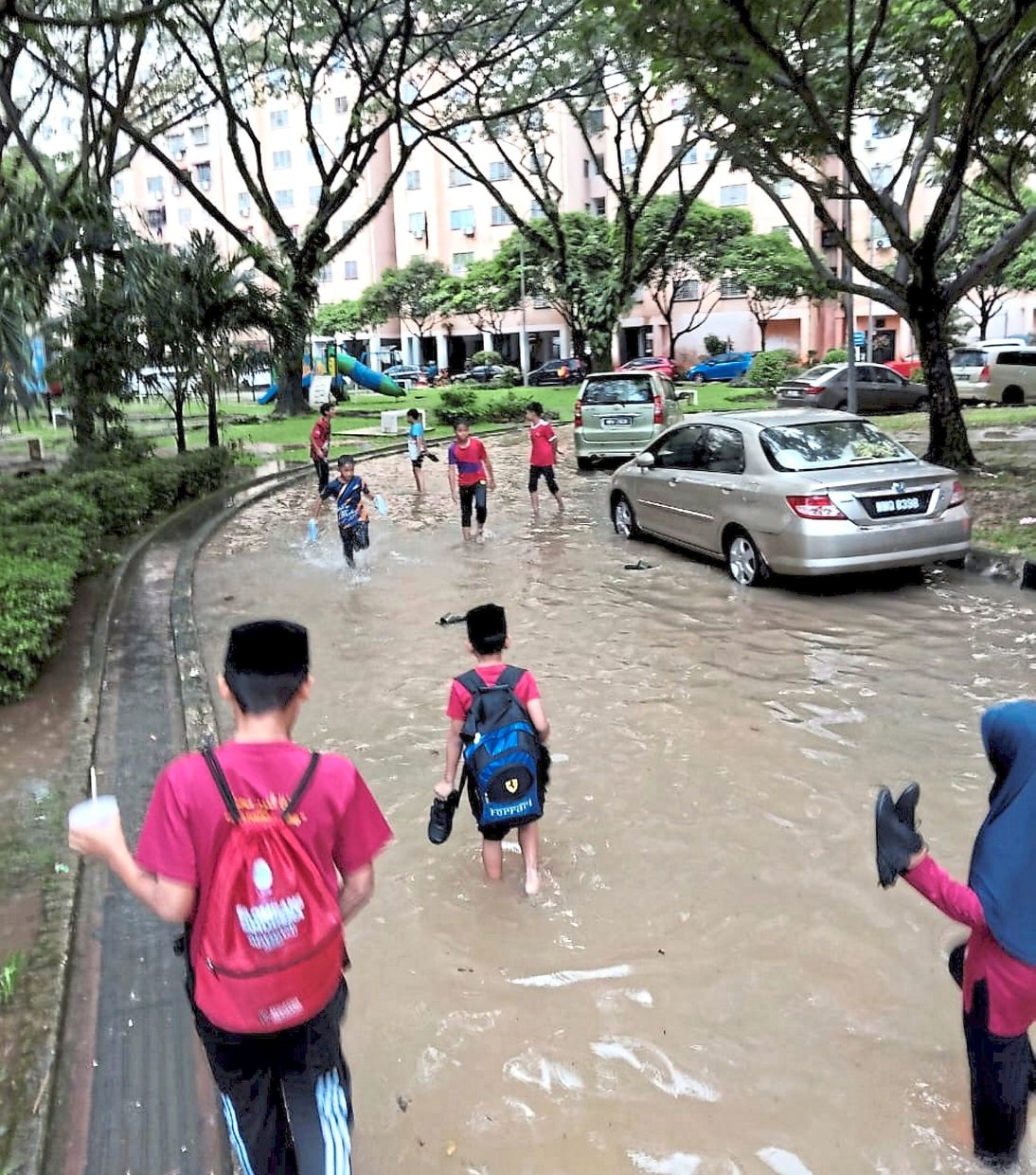 Residents wading through knee-deep floodwaters along an internal road at PPR Kg Muhibbah after heavy rain. — Filepic