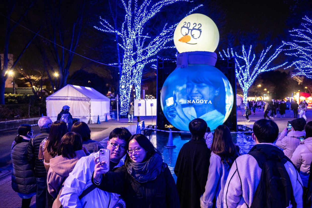 People take pictures with festive light installations ahead of Christmas in Tokyo's Shibuya district on Friday, December 19, 2025. --Photo by Philip FONG / AFP