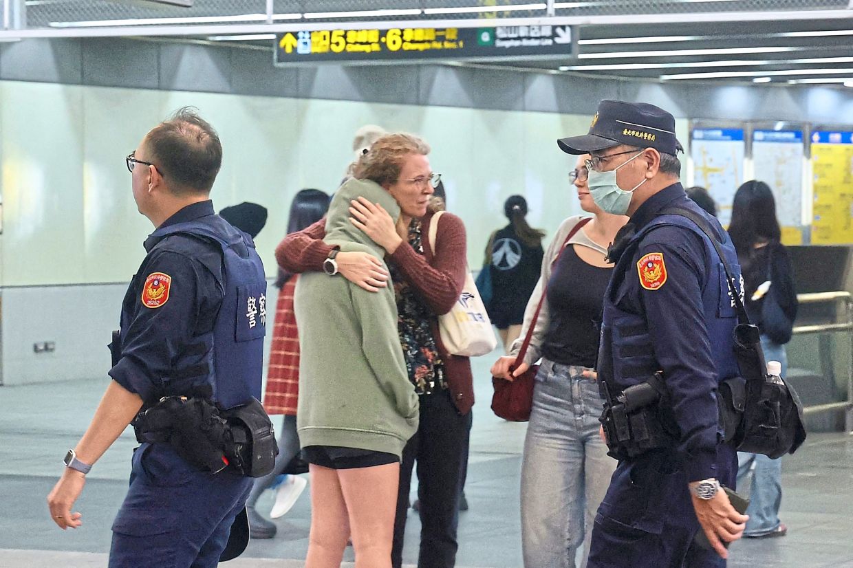 Keeping watch: A police officer patrolling at a metro station in Taipei and one of the entrances to Taipei Main Station being cordoned off after the attacks. — AFP/CNA