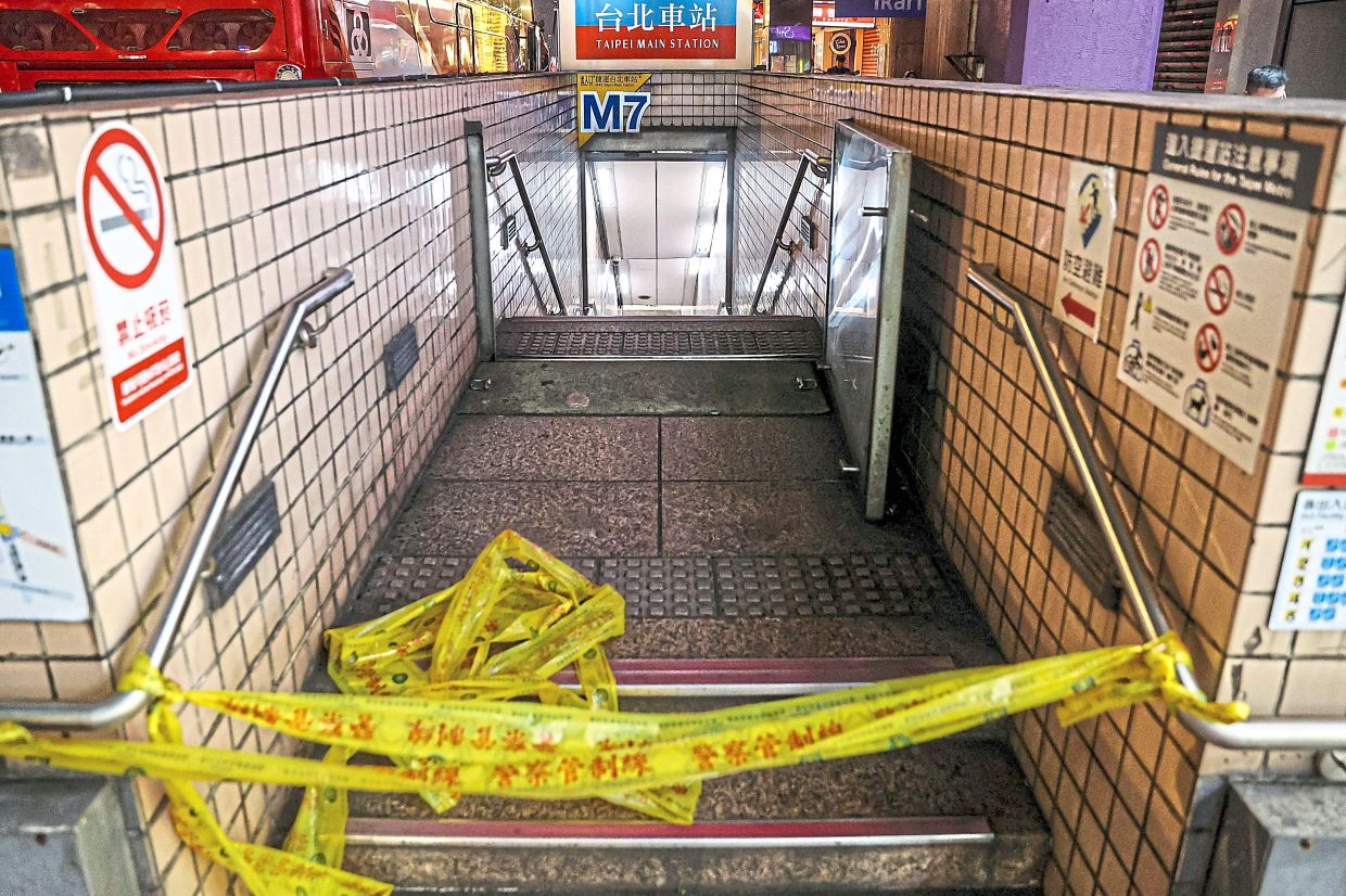Keeping watch: A police officer patrolling at a metro station in Taipei and one of the entrances to Taipei Main Station being cordoned off after the attacks. — AFP/CNA