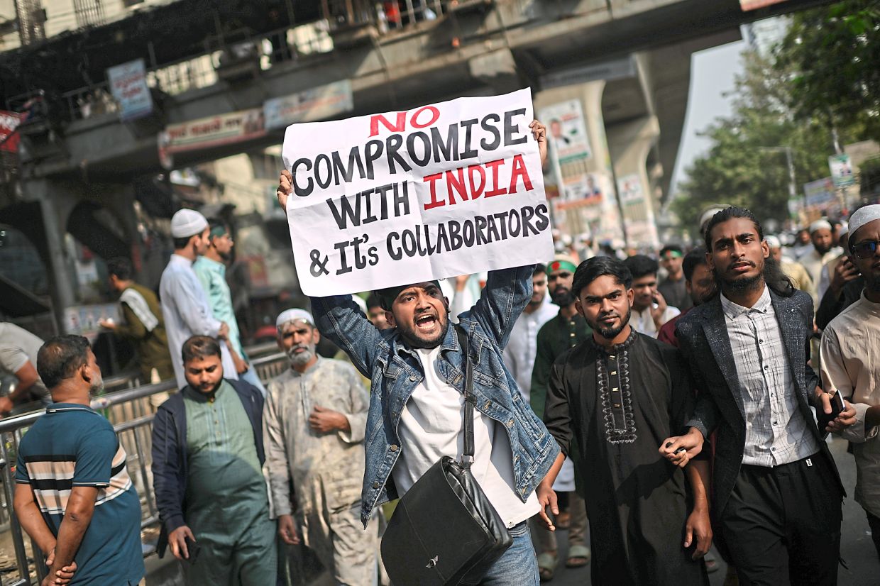 A protester holding a placard with shouting slogans after overnight attacks and vandalism in Dhaka. — Reuters/AP 