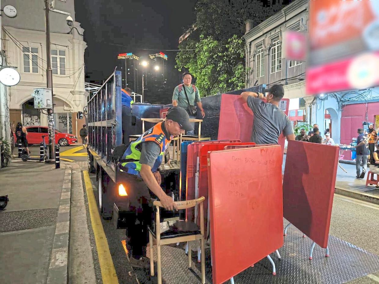 DBKL officers confiscating tables and chairs placed along a walkway during an enforcement operation in Jalan Petaling. — Filepic