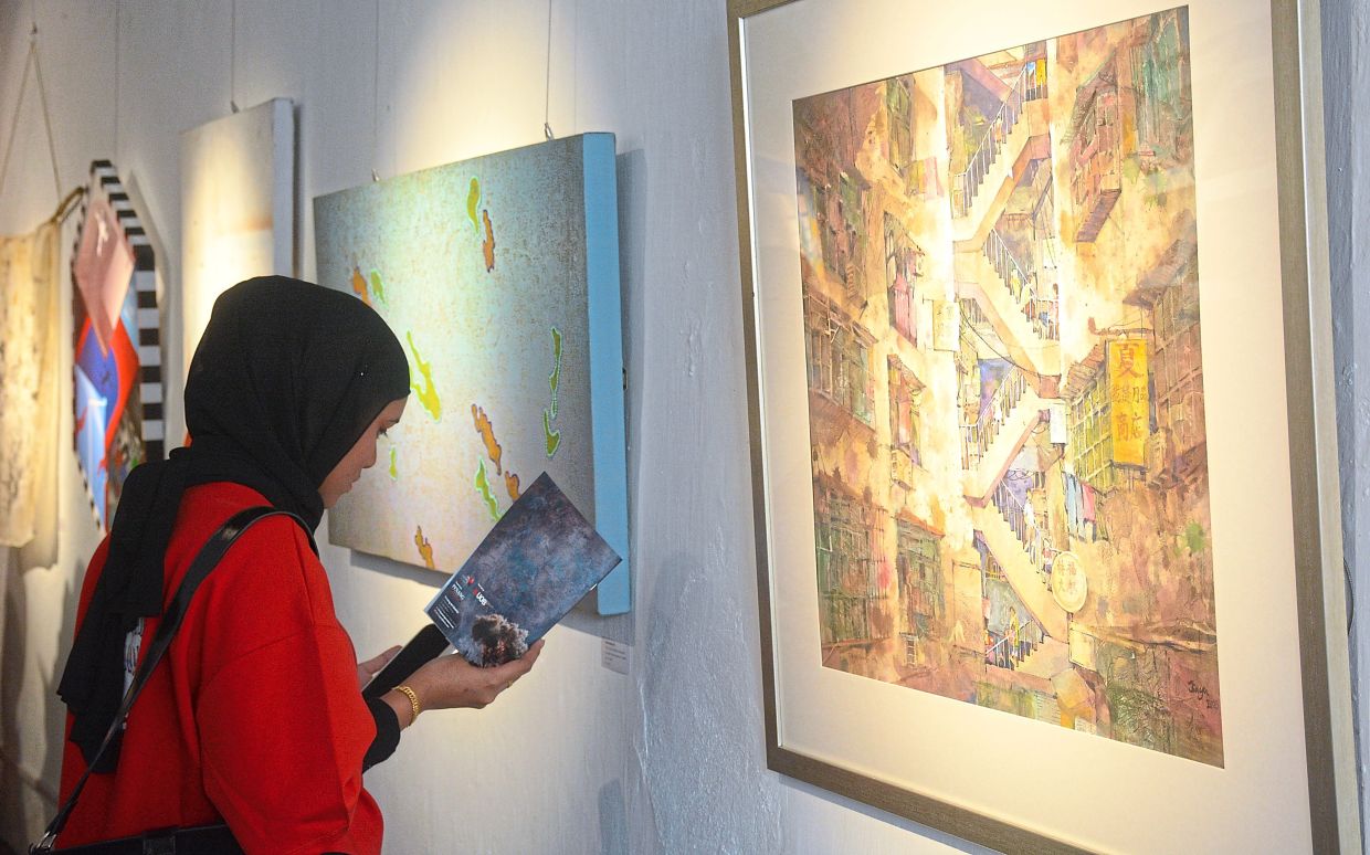 A gallery visitor reading the exhibition booklet which provides info on the artists and their artwork. 
