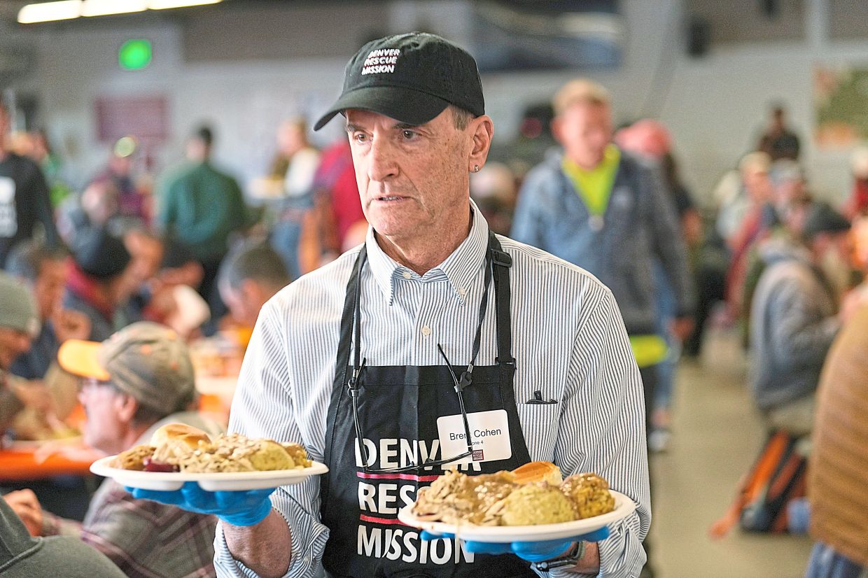 Volunteer Brent Cohen carries plates of food to guests during the annual Thanksgiving banquet at the Denver Rescue Mission in November 2023.
