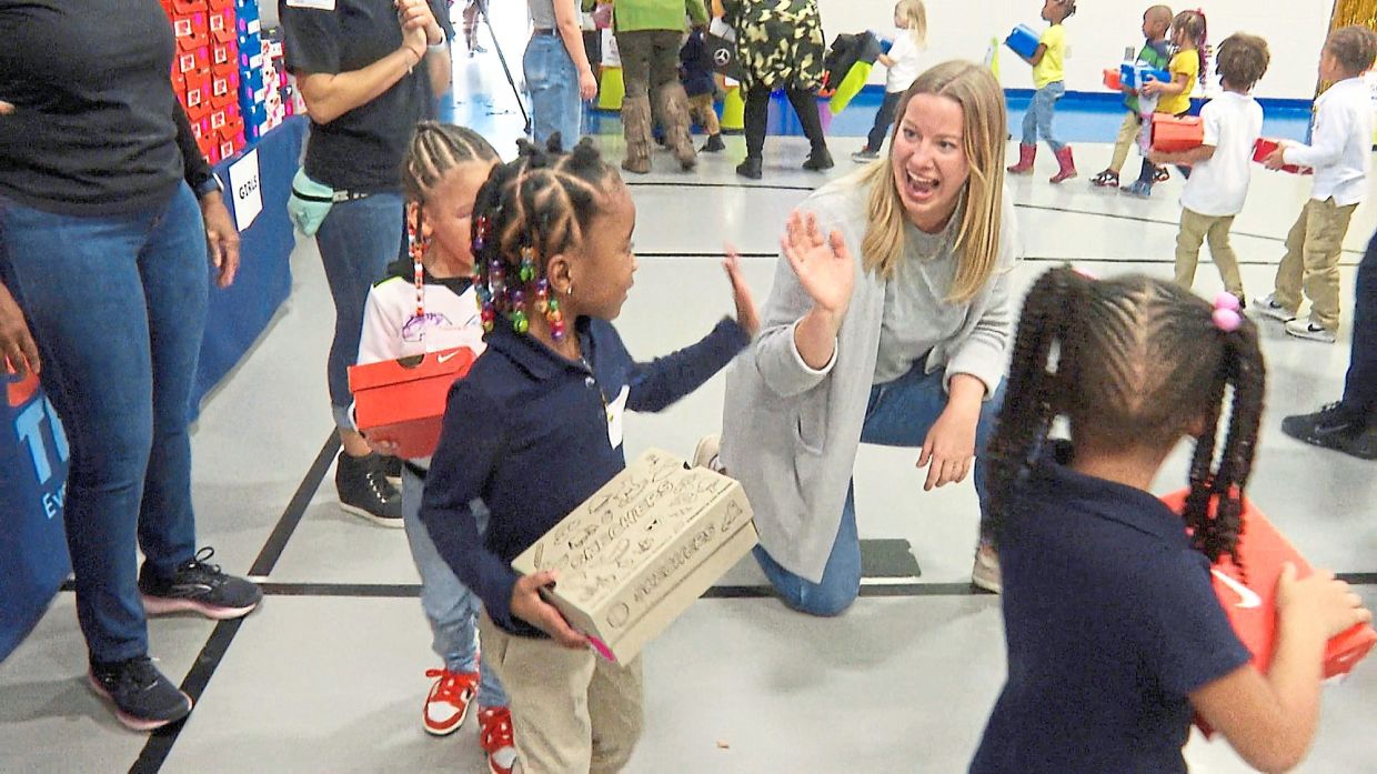 A volunteer waves to a student as she waits in line at Miles Intermediate Elementary School in Atlanta after receiving new shoes from Mercedes-Benz USA, as part of their Season to Shine holiday programme, in December 2022.