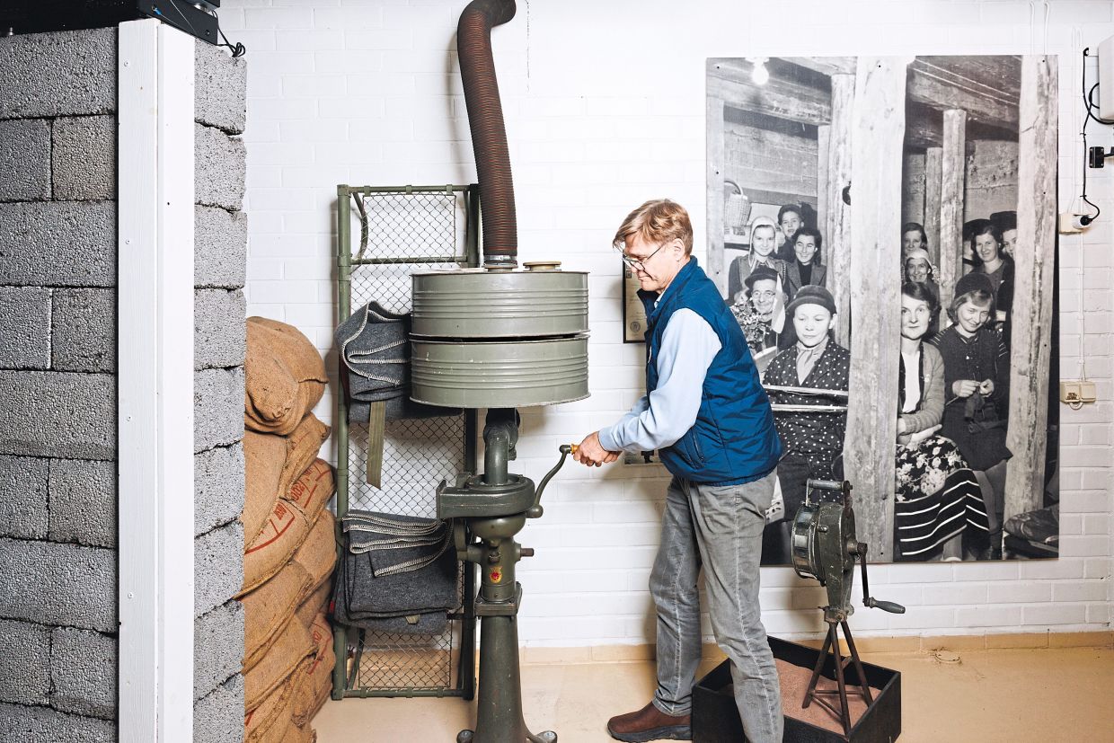 Lehtiranta demonstrates an early hand-cranked air filter that was made with a modified milk separator, at Helsinki’s Museum of Civil Defense.