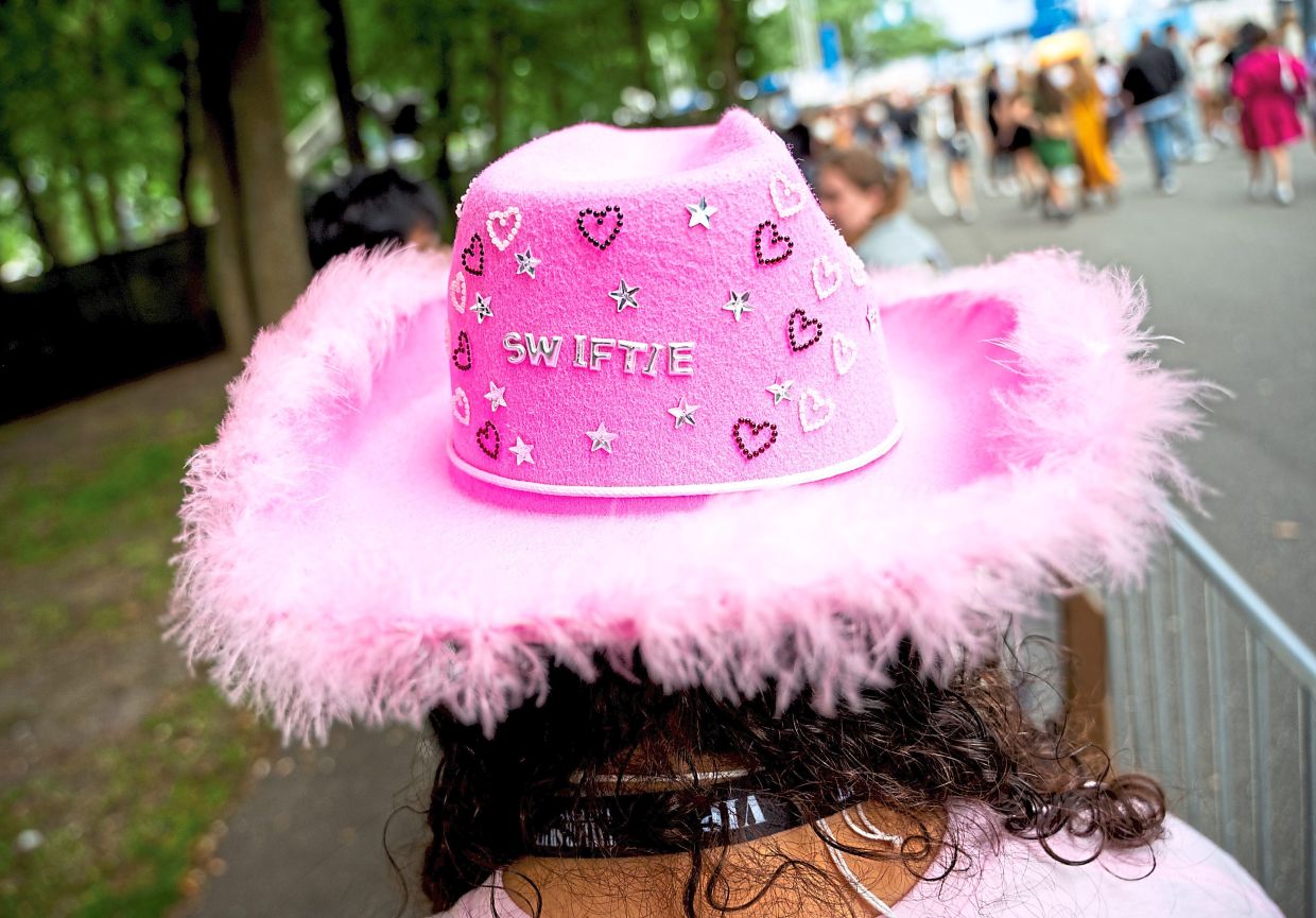 A fan of Swift waits for admission before a concert in Hamburg wearing a pink hat with the word 'Swiftie' on it. — DANIEL BOCKWOLDT/dpa