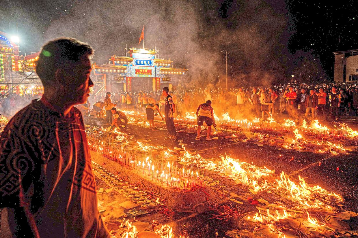Nocturnal festivities: People burning incense sticks while offering prayers during the Jiao Festival of Kam Tin. -AFP