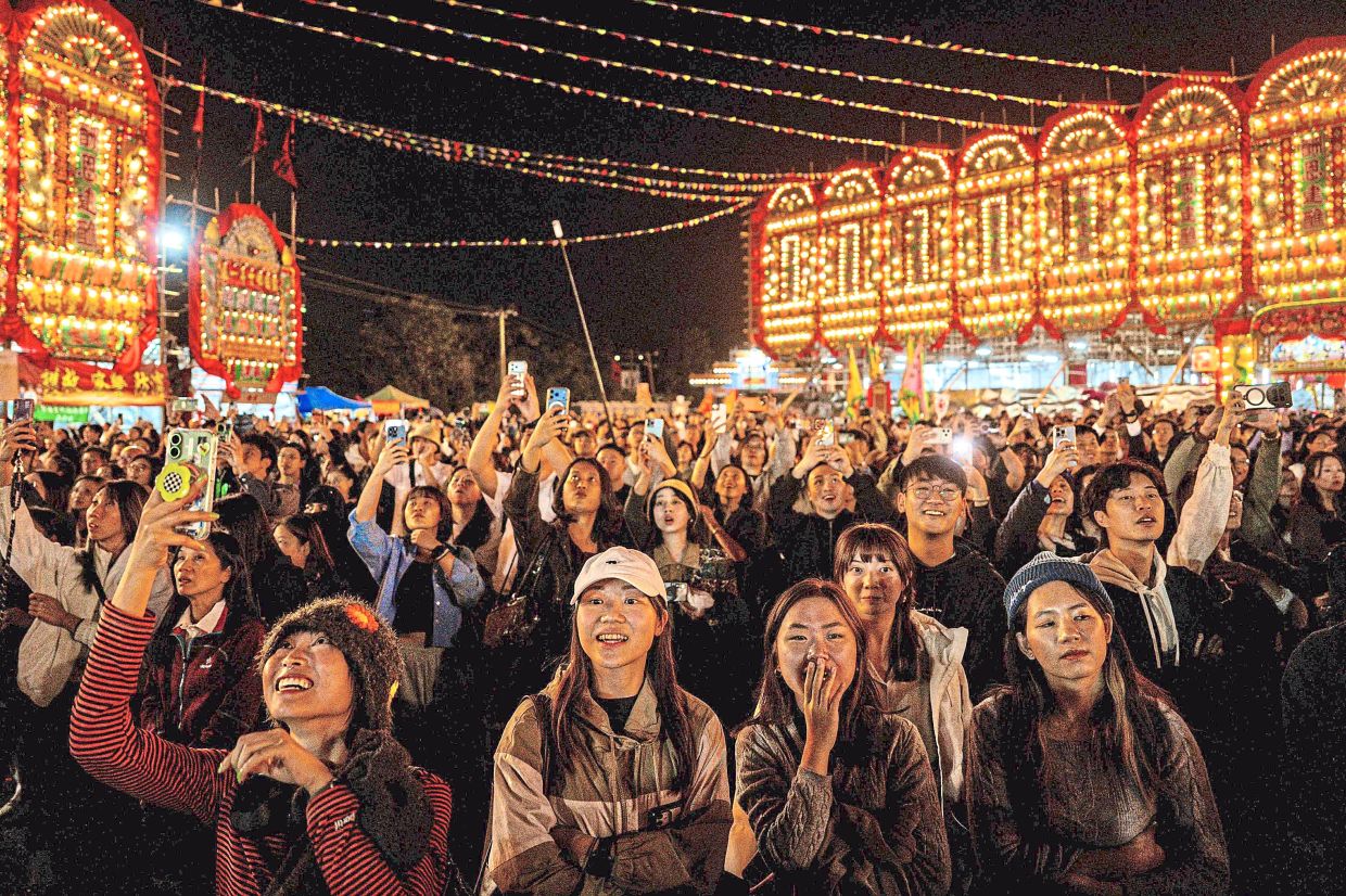 People watching a paper effigy of the Ghost King being paraded during the festival. — AFP