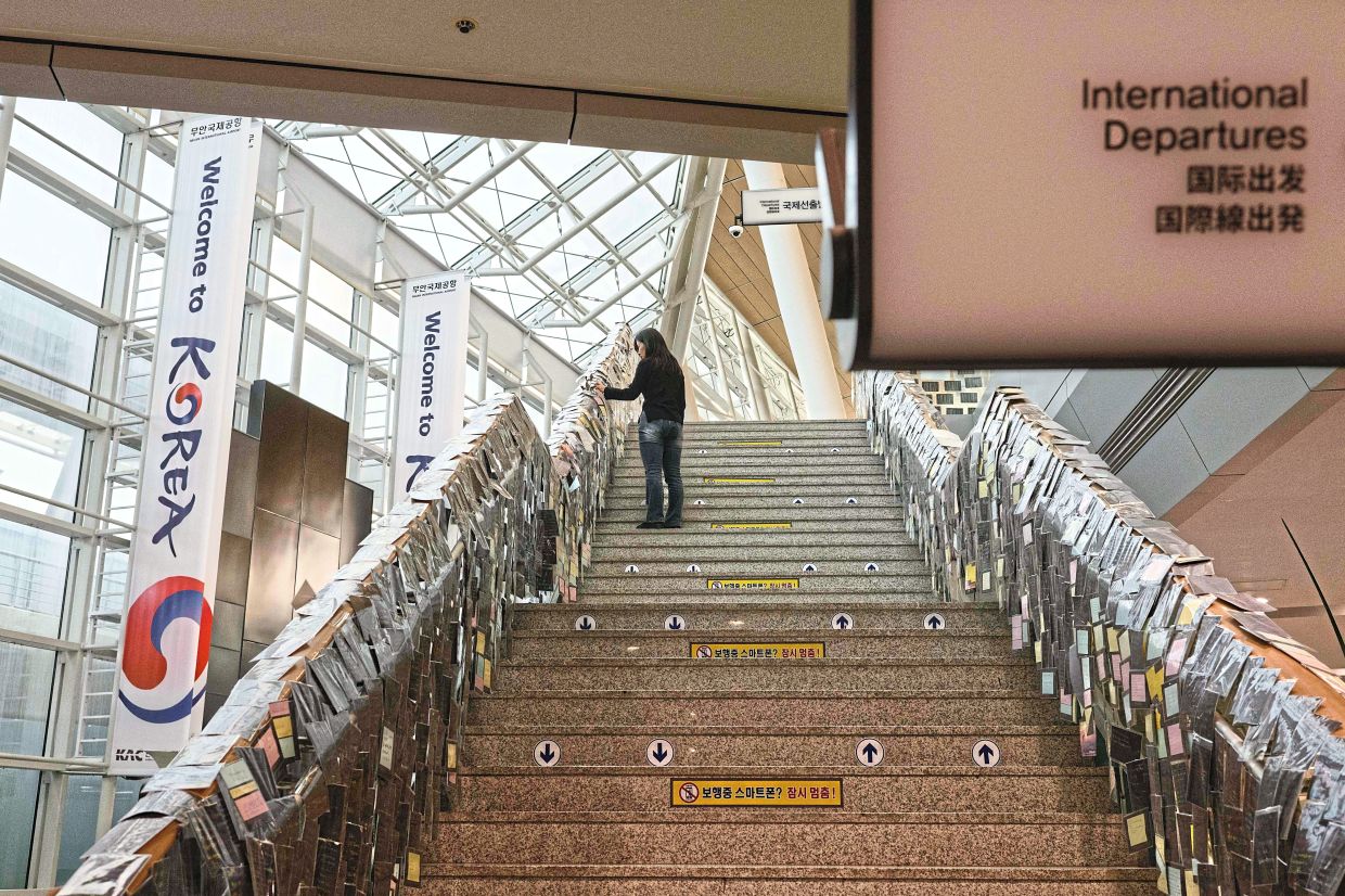 Words of comfort: Lee looking at notes left for Ye-won and other victims who died in the Jeju Air Flight 2216 plane crash. — AFP