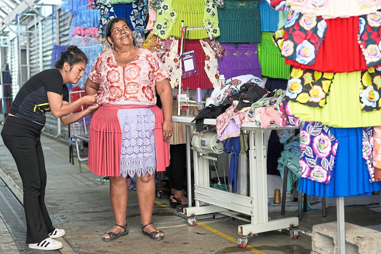 A dressmaker measures a customer at shop in Cochabamba, Bolivia, Monday, Sept. 15, 2025. (AP Photo/Juan Karita)