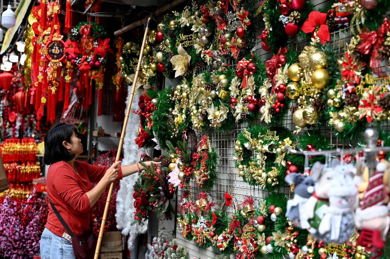A seller arranges Christmas decorations at her shop in Hanoi on Wednesday, December 24, 2025. -- Photo by Nhac NGUYEN / AFP