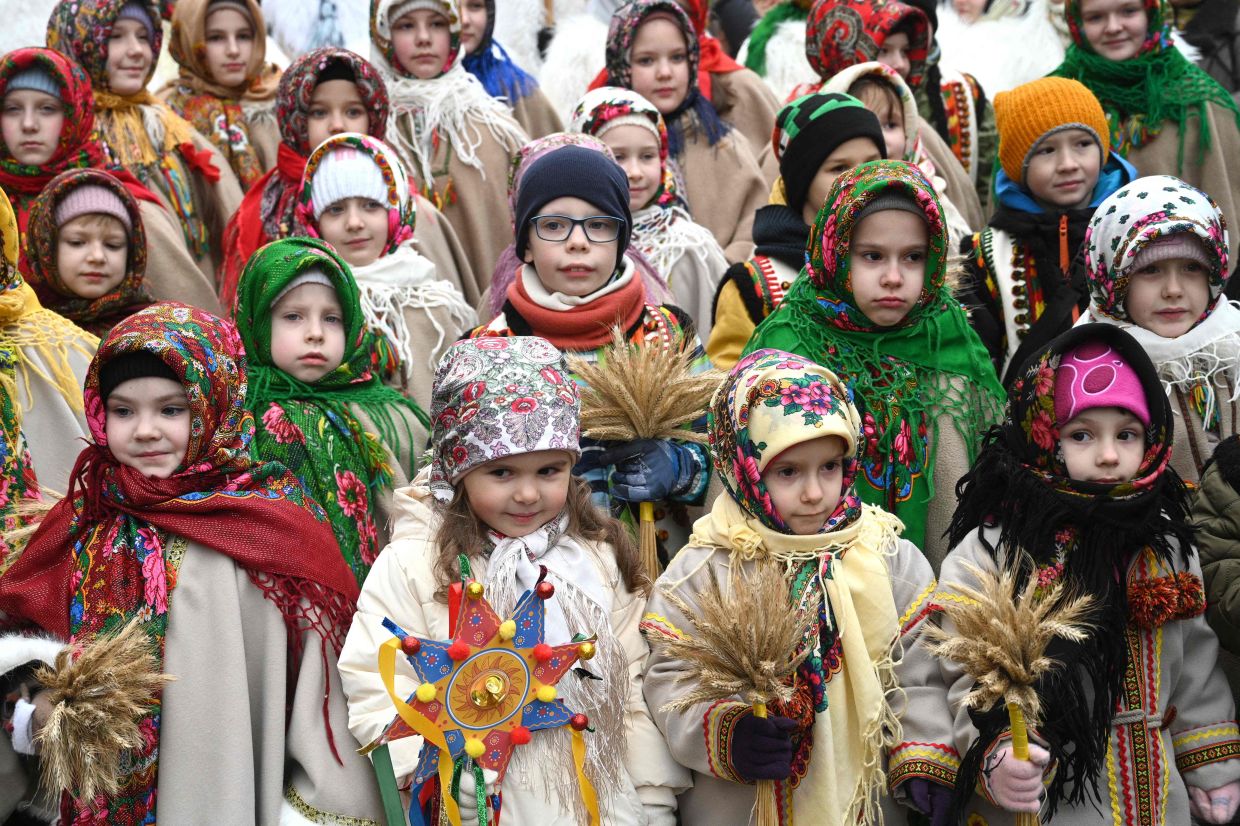 Children wearing traditional clothes and carrying Ukrainian traditional 'Didukh' Christmas decorations take part in a Christmas Eve procession in Lviv on Wednesday, December 24, 2025, amid the Russian invasion of Ukraine. Didukh is a decoration made of bunches of wheat, symbolising sacrifice and literally meaning the 'spirit of grandfather'. -- Photo by YURIY DYACHYSHYN / AFP