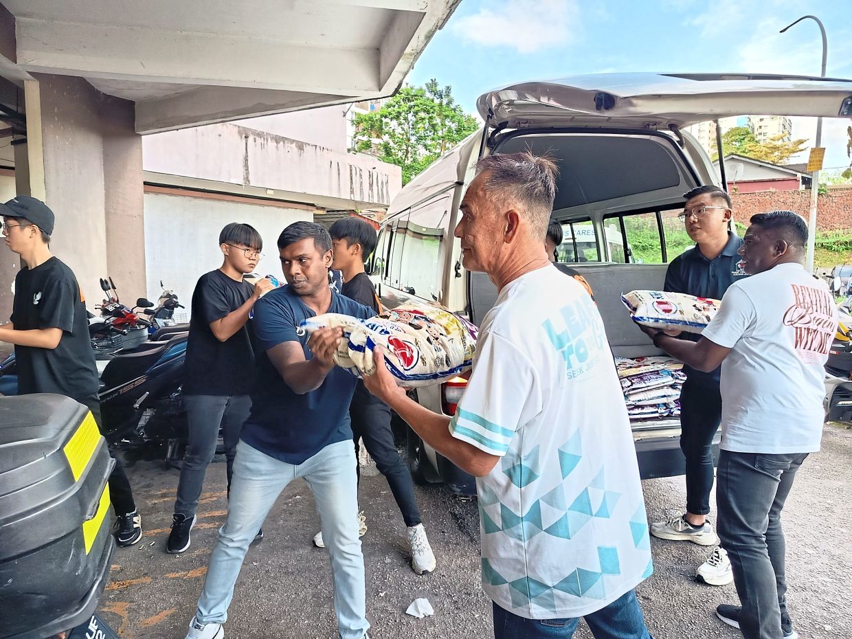 Volunteers from the Calvary Community Church distributing packs of rice to residents at a flat in Johor Baru.