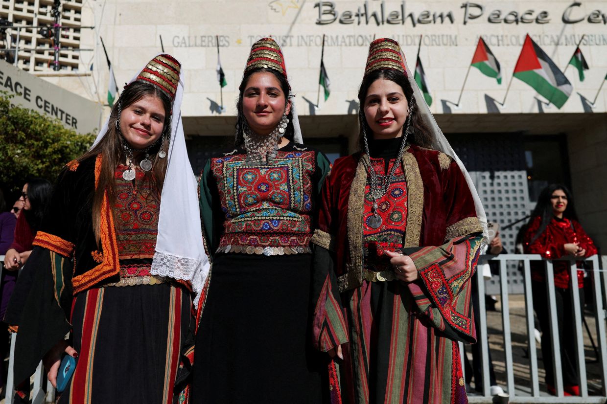 People in traditional dress pose for photos as Palestinian scouts march near the Church of the Nativity in Bethlehem. Photo: Reuters 