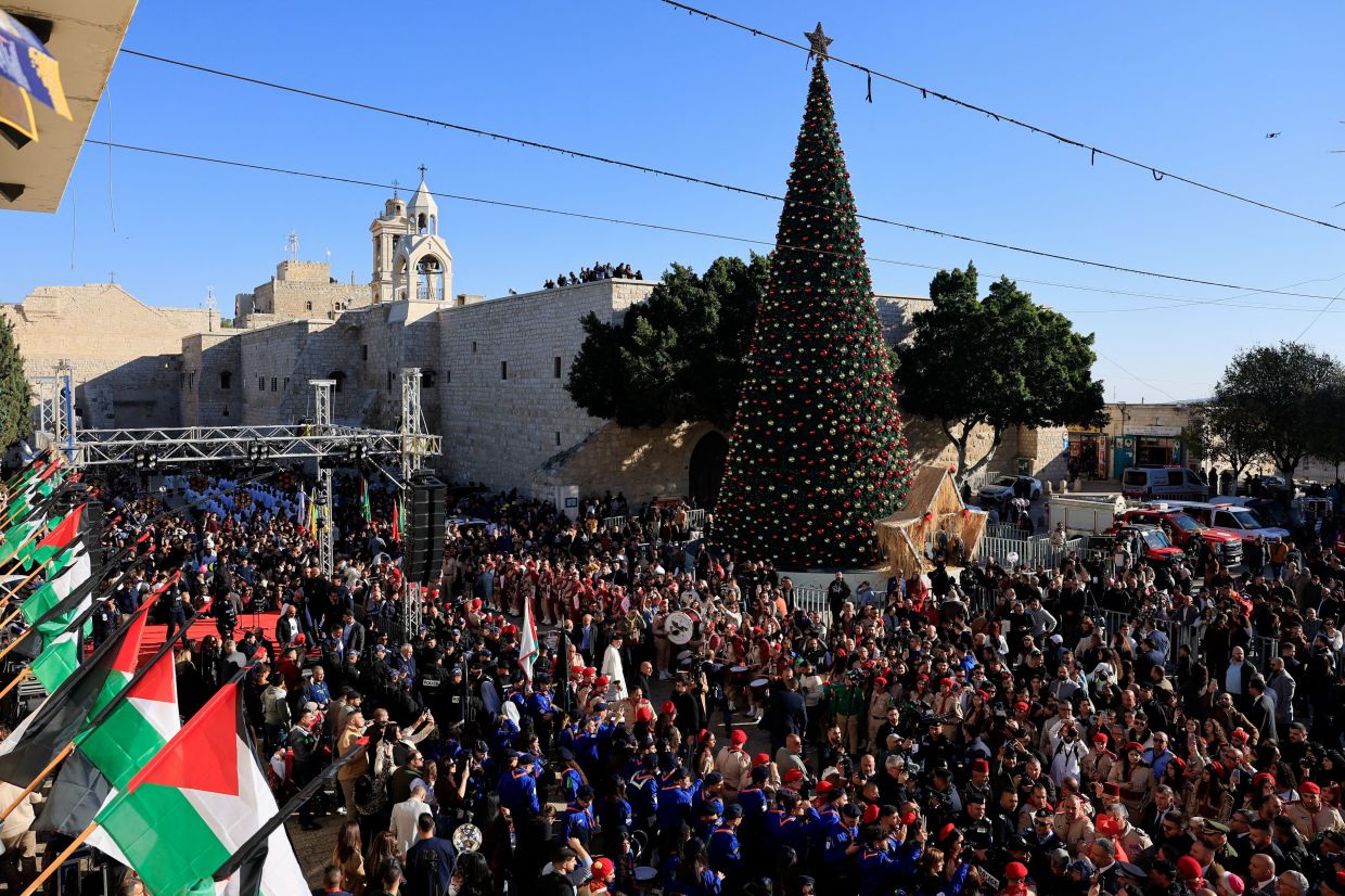 People gather next to the Christmas tree at Manger Square on the day of Christmas events in the Old City of Bethlehem in the Israeli-occupied West Bank. Photo: Reuters 