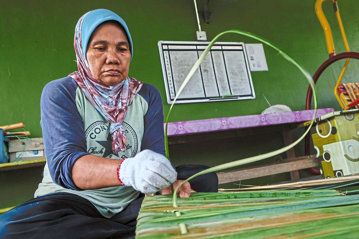 Saniah pinning on the nipah leaves. — Bernama 