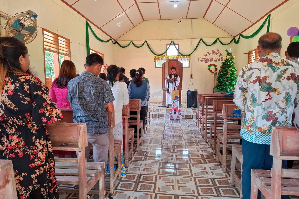 Villagers attend Christmas Mass at the Angkola Protestant Church at Aek Ngadol village, South Tapanuli, North Sumatra province, on December 25, 2025, in the aftermath of massive flooding and landslides in the area. At a church in Sumatra, dozens of worshippers sang hymns at a Christmas mass, holding their first service since floods and landslides killed more than 1,100 on the Indonesian island. -- Photo by AMROE / AFP