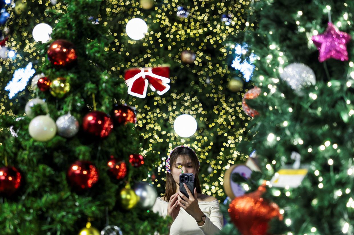 A woman takes a picture as she visits illuminated decorations assembled for Christmas and New Year's celebrations, at a department store in Bangkok, Thailand, December 25, 2025. -- Photo: REUTERS/Chalinee Thirasupa