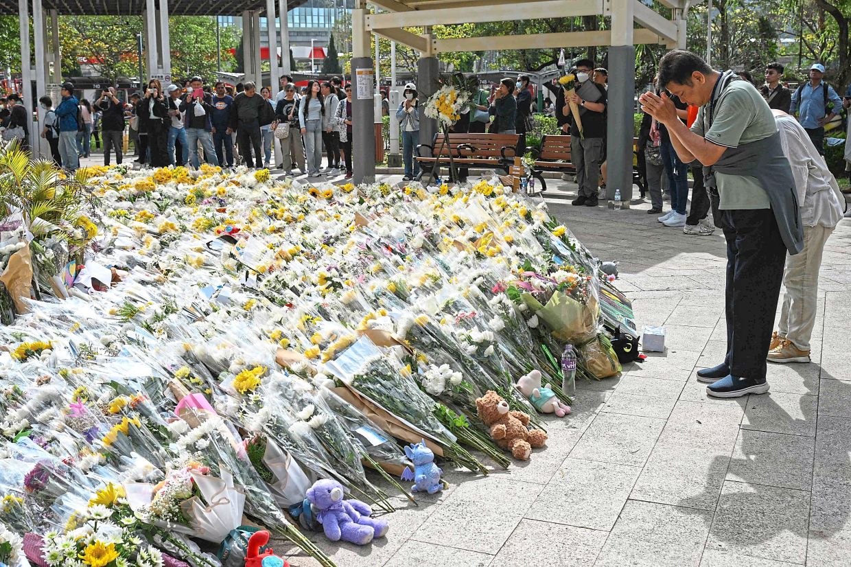 people laying flowers outside the complex after the fire. -AFP