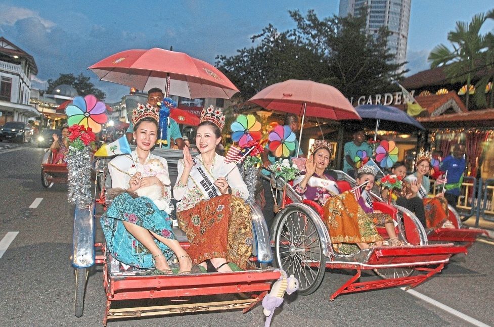 Peranakan women in trishaws adding colour to the parade.