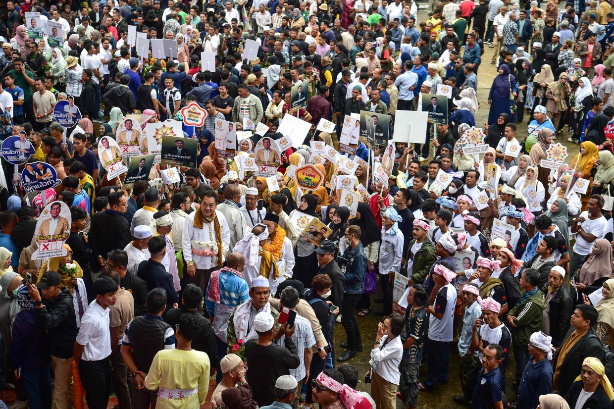 Supporters of the Prachachat Party (centre) hold placards on the first day of the registration for Thailand's upcoming general election at the provincial hall in the southern province of Narathiwat on Saturday, December 27, 2025. -- Photo by Madaree TOHLALA / AFP