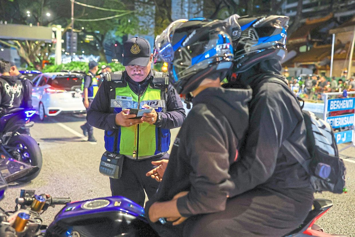 Not so fast: A JPJ officer inspecting the details of a motorcyclist during an operation throughout the capital city targeting vehicles involved in dangerous riding and illegal modifications. — Bernama