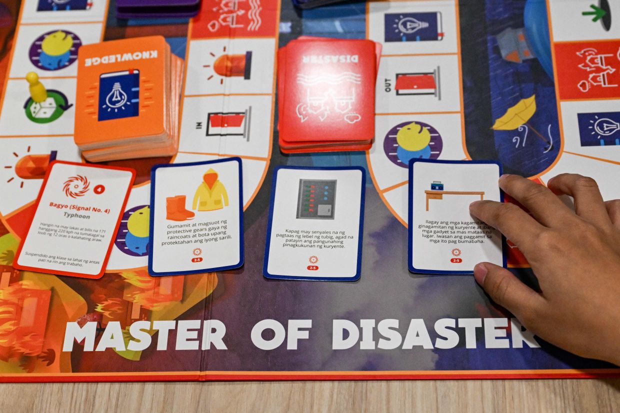 A participant placing response cards to a playing game that states 'Tropical Depression Signal No. 4 (left) as they play Master of Disaster. - AFP