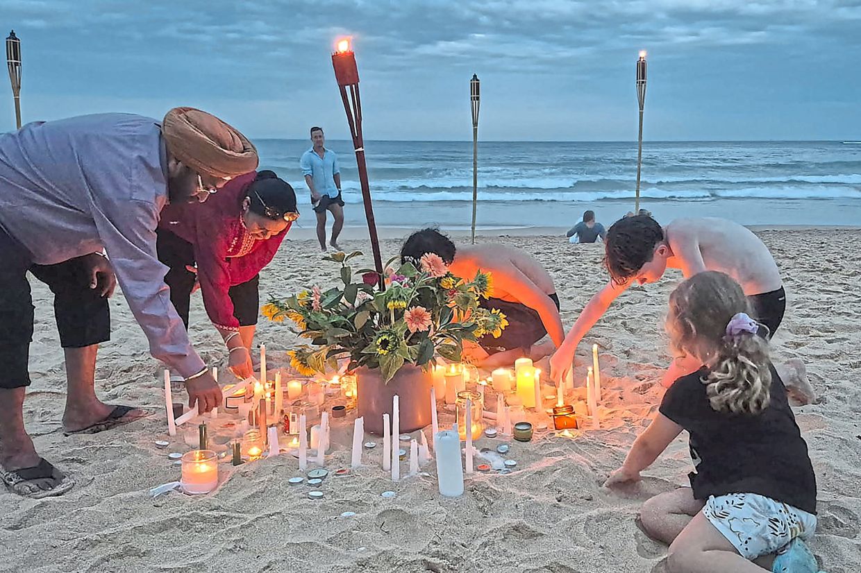 2. People lighting candles on Manly Beach in Sydney on Dec 21, as part of a national day of reflection honouring the victims of the Bondi Beach terrorist attack. — AFP