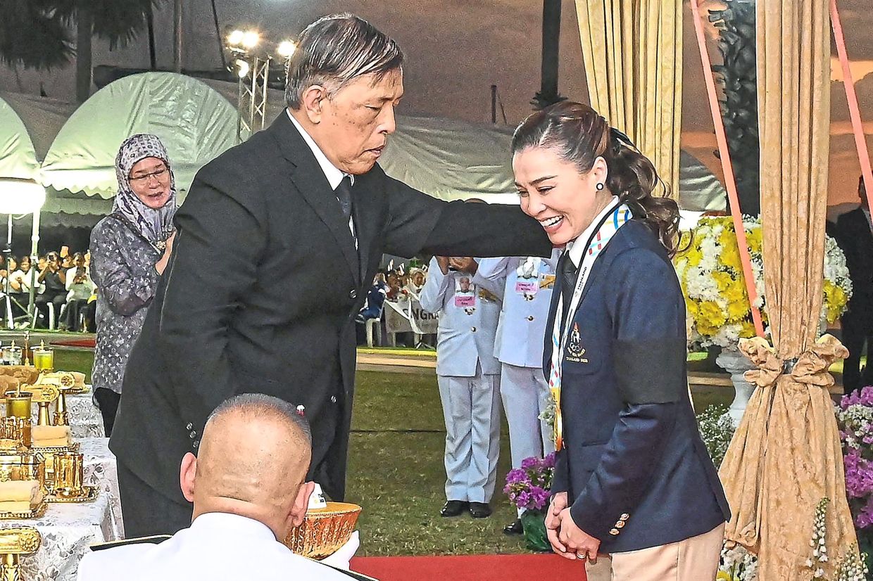 4. Thailand’s King Maha Vajiralongkorn presenting the gold medal to Queen Suthida after her victory in the mixed keelboat sailing event at the Ocean marina yacht club in Chonburi province. — Pool/AFP