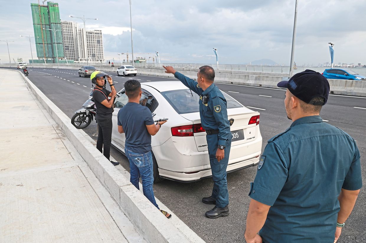 An MBPP enforcement officer advising motorists not to park their vehicles on the bridge. — CHAN BOON KAI/The Star