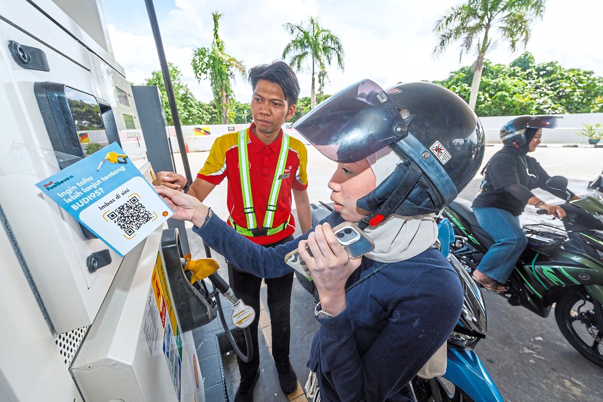 Fatin Nabila Widiyadi purchasing fuel under the Budi95 initiative at a petrol station. The programme is designed to make fuel subsidy access easier through seamless and cashless transactions. — ZULAZHAR SHEBLEE/The Star