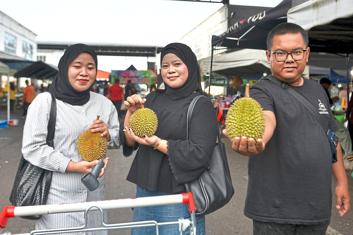 Happy indeed: Sisters Atikah and Kamariah posing for a picture as they select their fruits. — Bernama 