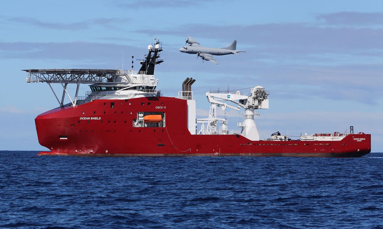 (FILES) This handout photo taken and released on April 9, 2014 by Australian Defence shows a Royal Australian Air Force AP-3C Orion flying past Australian Defence Vessel Ocean Shield on a mission to drop sonar buoys to assist in the acoustic search for missing Malaysia Airlines flight MH370 in the southern Indian Ocean. A Beijing court ordered Malaysia Airlines on December 8, 2025 to pay compensation to the families of eight passengers from flight MH370, more than a decade after the plane disappeared. (Photo by LSIS BRADLEY DARVILL / AUSTRALIAN DEFENCE / AFP)