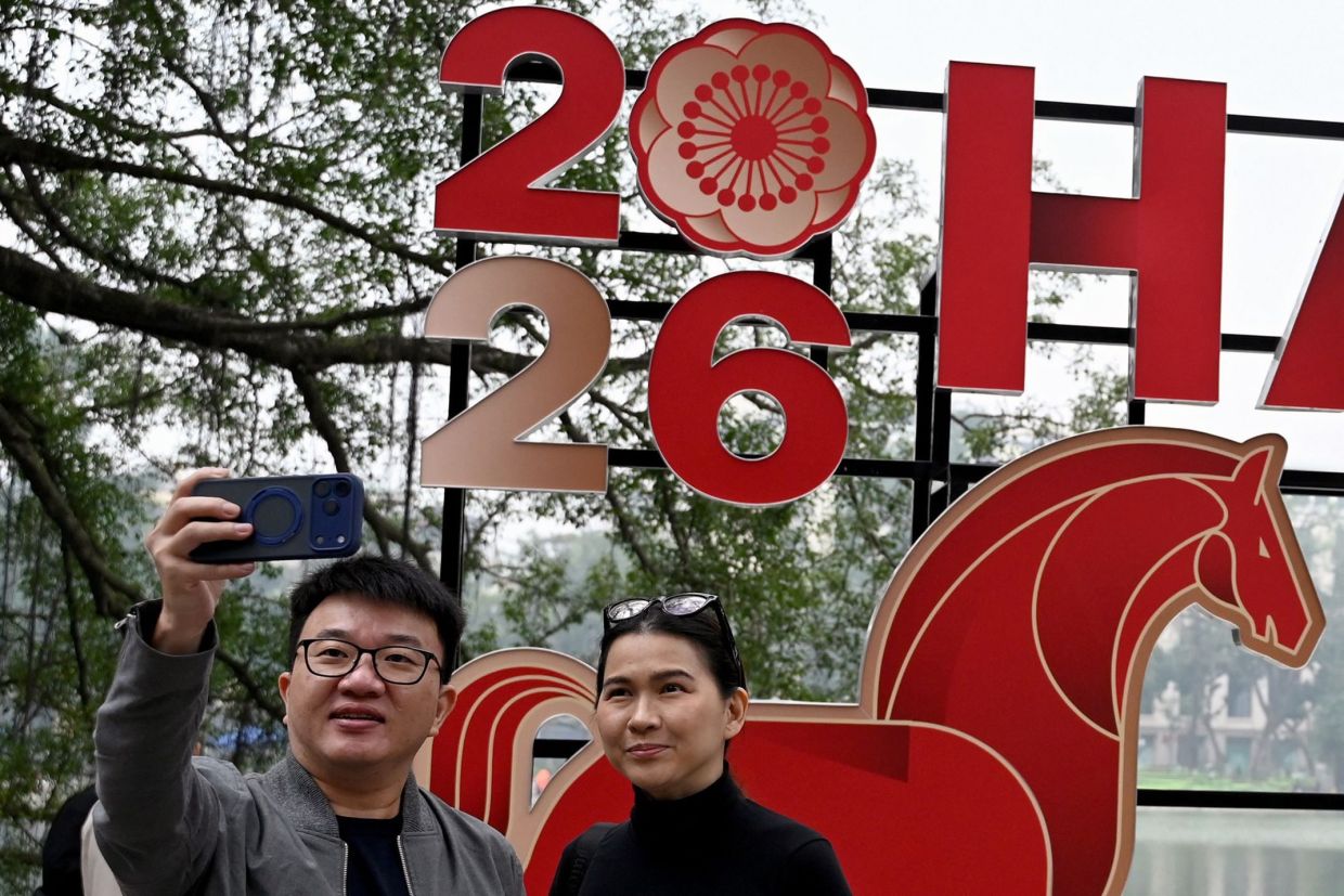 A couple taking a selfie next to a New Year's banner in Hanoi on Dec 31, 2025. - AFP