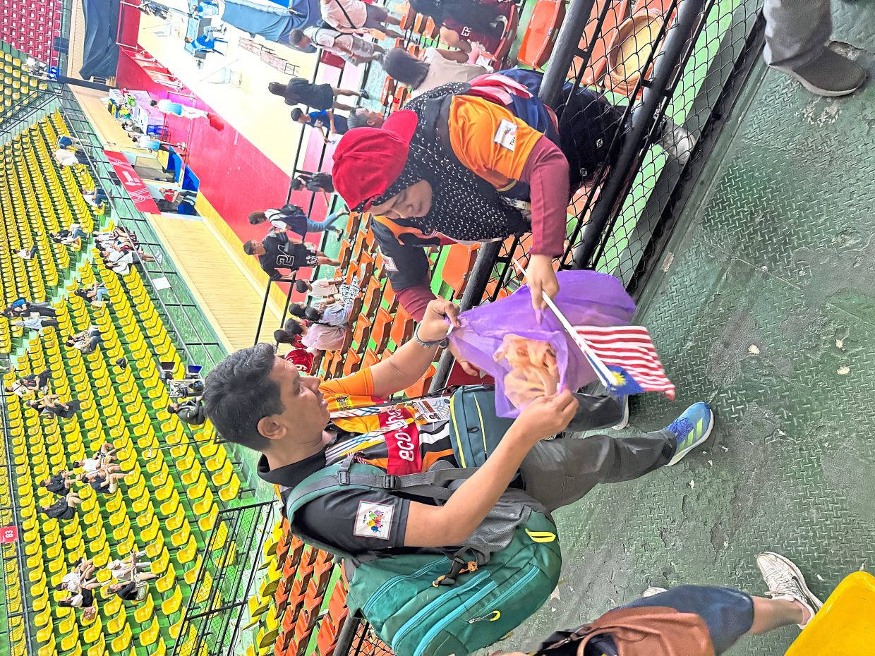 Hafidz Atrash (left) and Suriati Yusnita collecting rubbish left behind by spectators after the basketball match between Malaysia and Singapore at Nimibutr Stadium in Bangkok. 