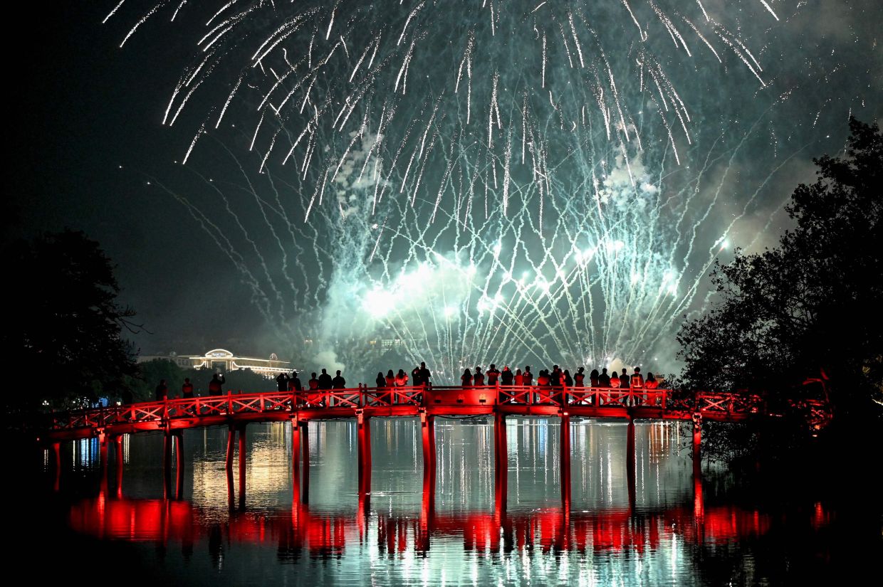 Revellers watch the New Year's Eve fireworks from the The Huc Bridge at Hoan Kiem Lake in Hanoi on January 1, 2026. -- Photo by Nhac NGUYEN / AFP