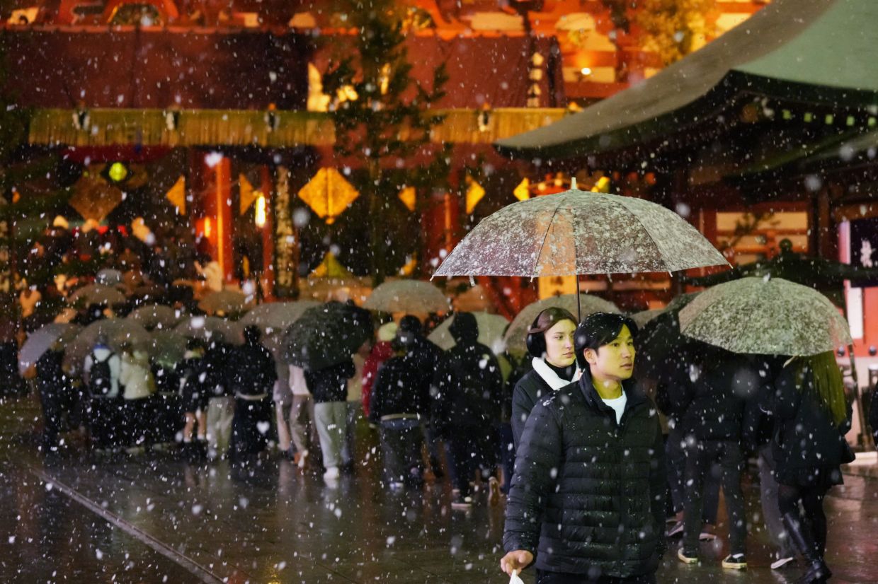People use umbrellas under the snow outside the Sensoji temple as people gather for the New Year's prayer in Tokyo, on Friday, Jan 2, 2026. -- AP Photo/Hiro Komae