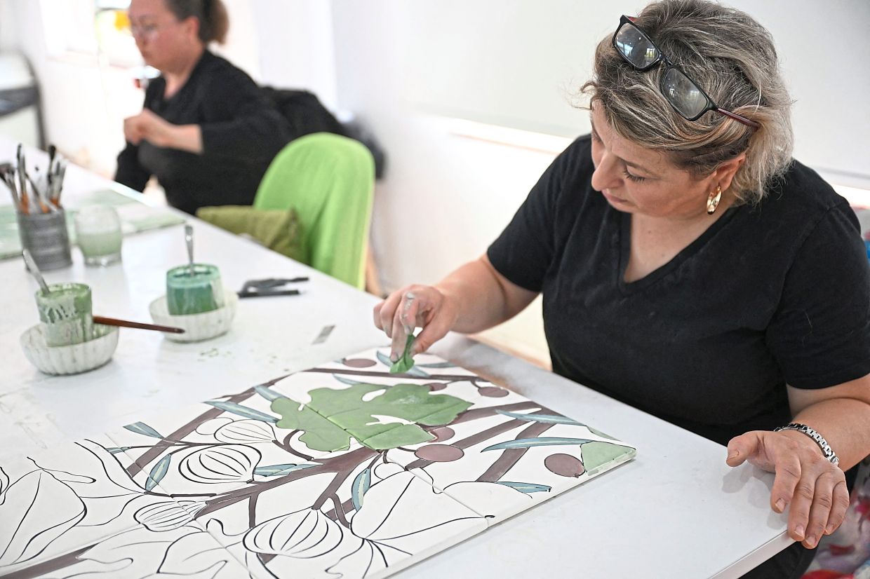 A woman painting tiles in a workshop in Iznik. — AFP