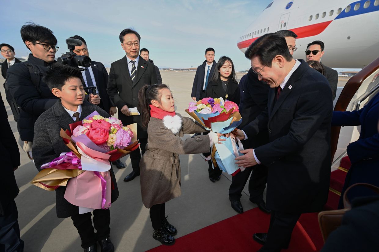 South Korean President Lee Jae Myung (right) receives flowers from a child as he and his wife Kim Hea Kyung arrive at Beijing Capital International Airport for their official visit, in Beijing, China, on Sunday, Jan 4, 2026. -- Photo: Dai Tianfang/Xinhua