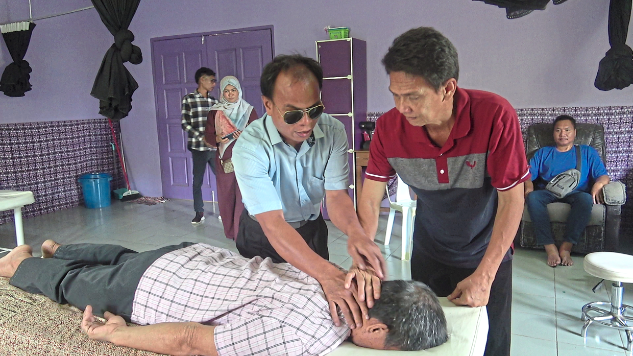 A senior instructor guiding trainees through massage therapy practice, one of the key income-generating skills taught at the centre.