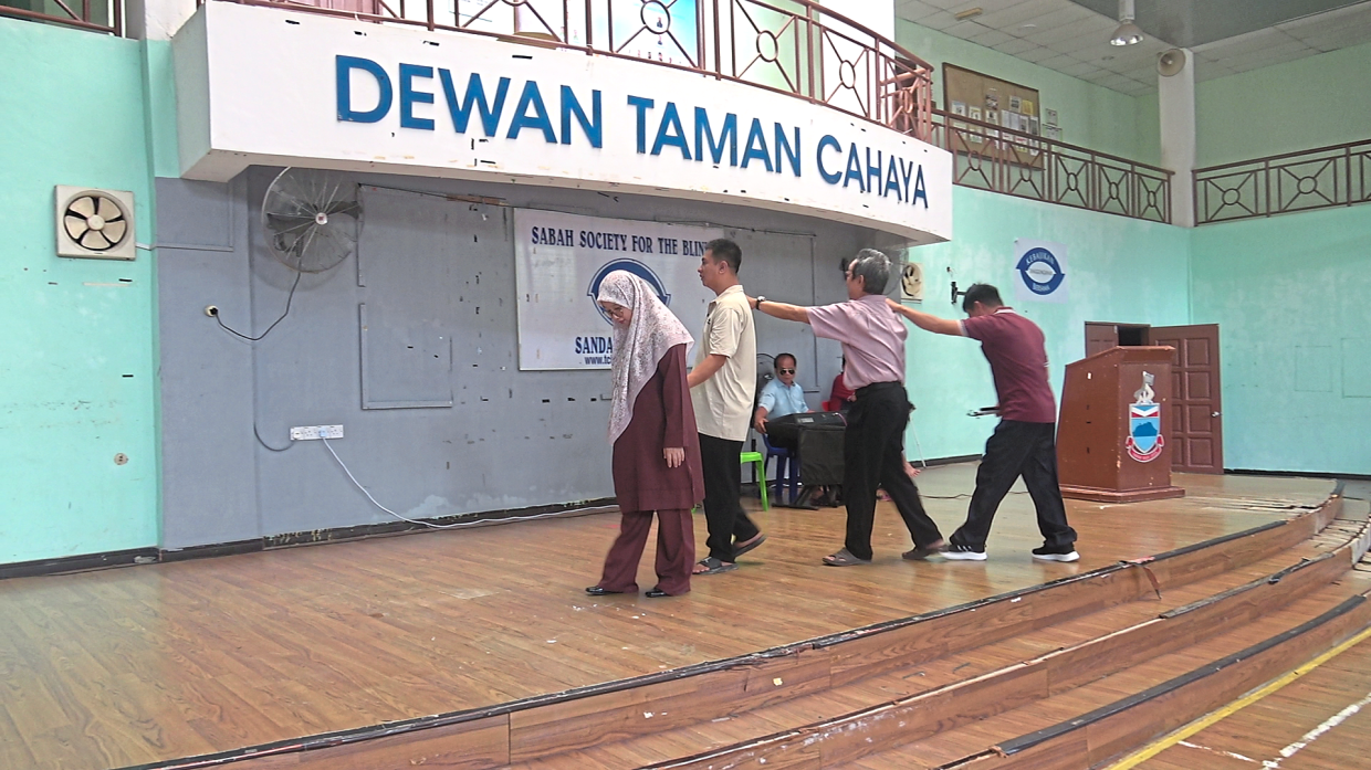 Trainees practising mobility and orientation exercises on stage at the Taman Cahaya centre.