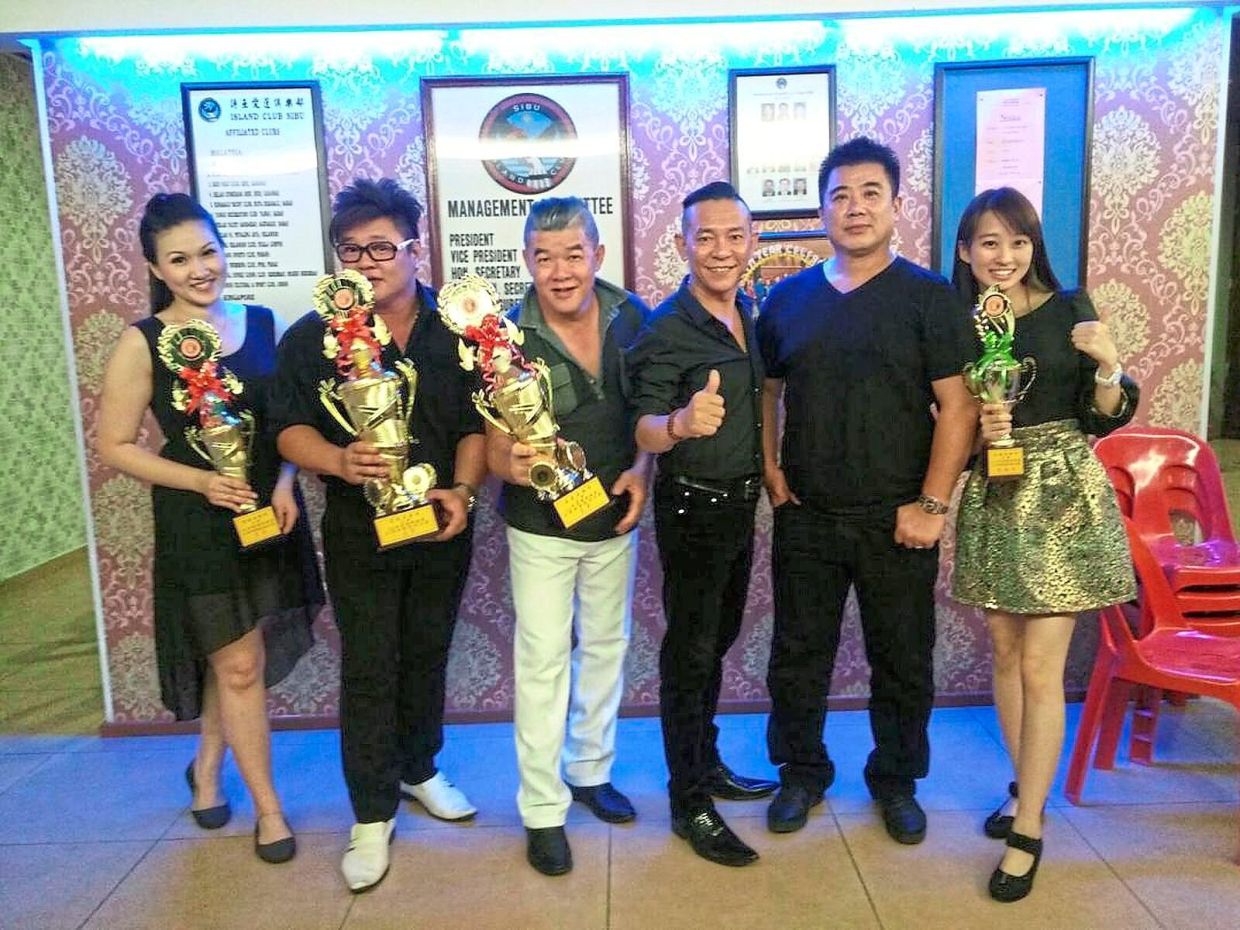 Winners of a singing competition held at the club celebrating with their trophies.