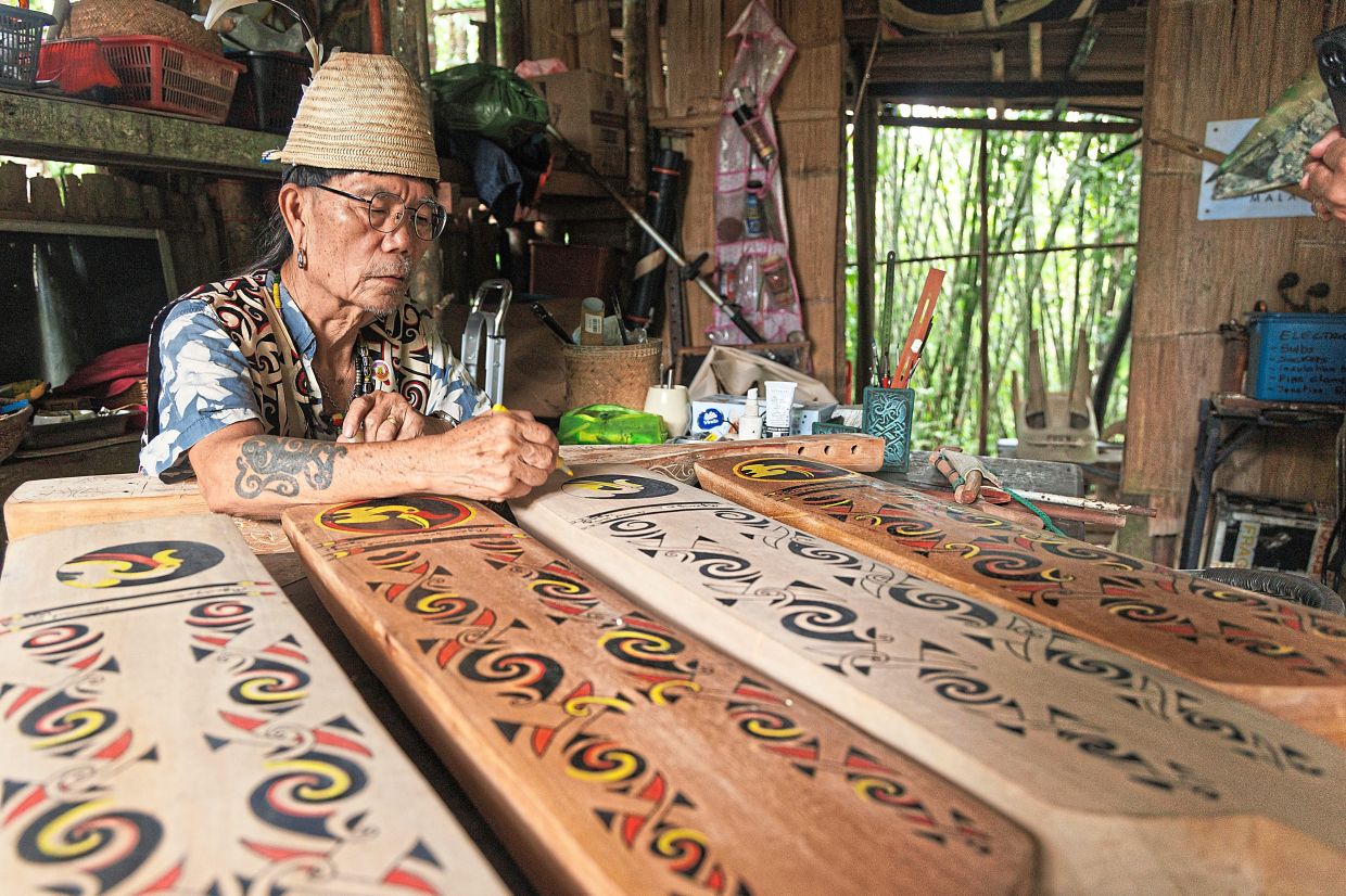 Mathew decorating a sape with traditional Orang Ulu motifs. — Photos by ZULAZHAR SHEBLEE/The Star